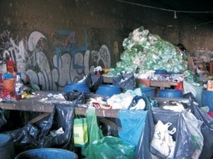 Mesa usada para triagem do lixo. Ao redor as bombonas que separam os materiais por tipo